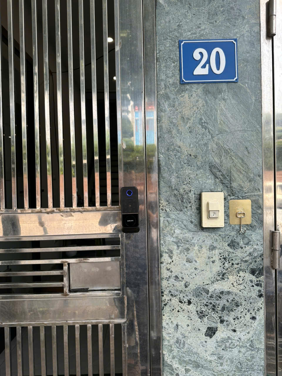 Mặt ngoài khóa vân tay Avolock AG-47 lắp đặt thực tế trên cửa cổng inox nan, đèn nhận diện vân tay phát sáng